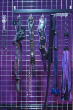 Image of BDSM collars, flails & other equipment hanging on a bondage bed